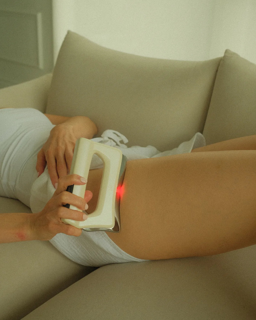 Lying on the couch with FasciaWave glowing red on the outer hip